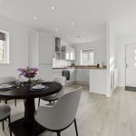 Modern kitchen-diner with wooden floors and white cabinets.