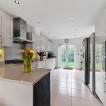 Modern kitchen with white cabinets and garden view.