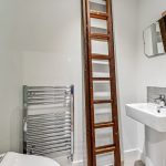 Small bathroom with sink, ladder, and towel rack.