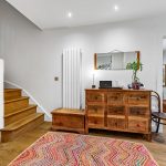 Cosy hallway with wooden furniture and colourful rug.