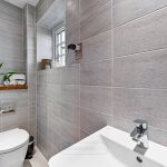 Modern bathroom with grey tiles and plant decor.