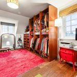 Organised walk-in wardrobe with red rug and window