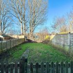 Back garden with wooden fences and trees.