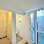 Small brick bathroom with frosted glass door.