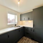 Modern kitchen with dark cabinets and stainless sink.
