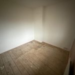 Empty room with wooden floorboards and white walls.