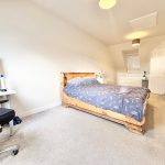 Modern bedroom with wooden bed and workspace desk.