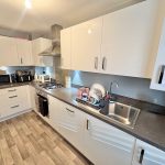 Modern kitchen with white cabinets and appliances.