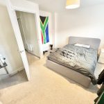 Bedroom with grey bed and South African flag.