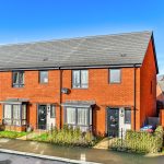 Modern red-brick terraced houses under clear blue sky.