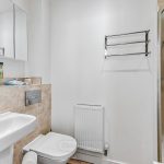 Modern bathroom with white fixtures and tiled walls.