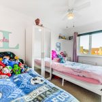 Children's bedroom with toys and two beds.