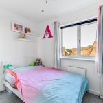 Bright child's bedroom with pastel rainbow bedspread.