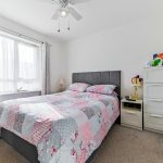 Bright bedroom with floral bedspread and drawers.