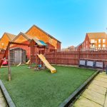 Garden with playground and slide in sunny backyard.