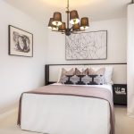 Modern bedroom with artwork and chandelier.