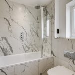 Modern marble bathroom with bathtub and shower.