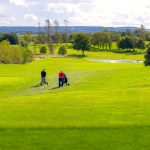 Golfers walking on a sunny golf course path