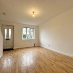 Empty room with wood flooring and window.