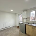 Minimalist kitchen with boiler, sink, and window.