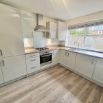 Modern kitchen with wooden floor and white cabinets.