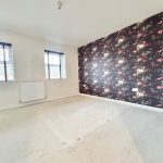 Empty room with floral wallpaper accent wall.