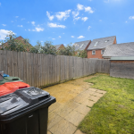 Back garden with bins and shed under blue sky.