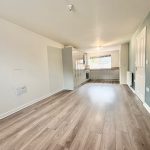 Spacious kitchen with wooden flooring and modern cabinets.