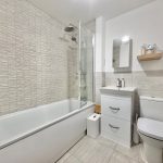 Modern bathroom with white fixtures and tiled walls.