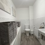 Modern bathroom with wicker storage baskets and artwork.