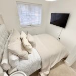 Cosy bedroom with modern decor and wall-mounted TV.
