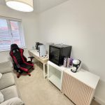 Gaming room with chair, consoles, and coffee machine.