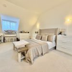 Spacious modern bedroom with neutral decor and lighting.