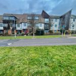 Modern UK residential apartment buildings along the street.