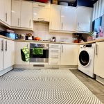 Modern kitchen with white cabinets and appliances.