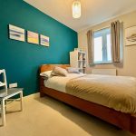 Cosy bedroom with teal accent wall and artwork.