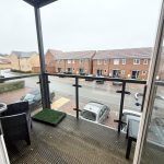 Covered balcony overlooking residential street with parked cars.