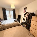 Cosy bedroom with bed, wardrobe, and chest of drawers.