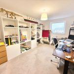 Home office with shelves, guitars, computers, and decor.