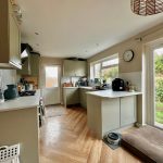 Modern kitchen with garden view through large window.