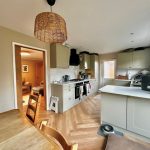 Modern kitchen with wooden floors and dining area.