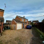 Brick house with driveway and parked car outside.