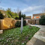 Back garden with grass, patio, and fence.