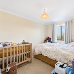 Bedroom with crib, bed, window, and soft toys.