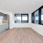 Modern kitchen with large windows and wooden flooring.