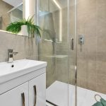 Modern bathroom with glass shower and white sink.