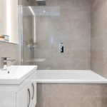 Modern bathroom with tiled walls and bathtub.