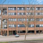 Four-storey brick office building with large windows.