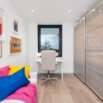 Bright home office with colourful sofa and art.