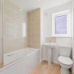Modern bathroom with bathtub and white tiles.